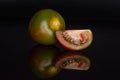 Greenish red tomato isolated on black glass