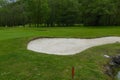 Greenkeeper is maintaining golf course with bunker and rake on sunny day Royalty Free Stock Photo