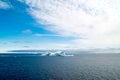 Greenlandic landscape with altocumulus clouds on blue sky over dark blue Arctic Ocean with iceberg, Greenland