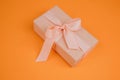 Greeting background. Gift wrapping in soft pink paper on a orange background with copy space Royalty Free Stock Photo