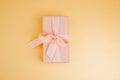 Greeting background. Gift wrapping in soft pink paper on a yellow background with copy space Royalty Free Stock Photo