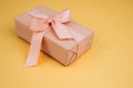 Greeting background. Gift wrapping in soft pink paper on a yellow background with copy space Royalty Free Stock Photo