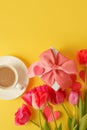 Greeting card. Bouquet of colorful tulip flowers, cup of coffee, gift box on yellow, copy space, invitation card. Spring time Royalty Free Stock Photo