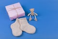 Greeting card with children`s socks, gift box and wooden teddy bear toy on blue background.