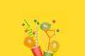 Greeting card with colored disposable cups with straws on a yellow background Royalty Free Stock Photo
