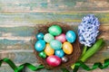 Greeting card on Easter from flowers and nest with colorful eggs on rustic wooden table top view. Traditional spring holiday. Royalty Free Stock Photo