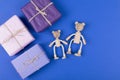 Greeting card with family of wooden teddy bears toy and gift box on blue background.