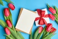 Greeting card with gift box, envelope and red tulips on blue paper background Royalty Free Stock Photo