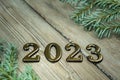 Greeting card happy new year 2023 on a background of white boards with a branch of a Christmas tree with bright lights Royalty Free Stock Photo