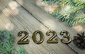 Greeting card happy new year 2023 on a background of white boards with a branch of a Christmas tree with bright lights Royalty Free Stock Photo