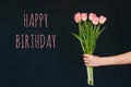 Greeting card with the inscription happy birthday. Bouquet of pink Tulip flowers in a woman`s hand Royalty Free Stock Photo