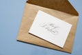 Greeting card with the inscription Merry Christmas on a brown craft envelope on a blue background Royalty Free Stock Photo