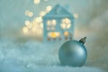 Greeting card Merry Christmas. Blue house is covered with snow, a ball, a garland and green branches. Soft focus Royalty Free Stock Photo