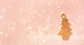 Greeting card in minimal style. Wooden Christmas tree on pink background with copy space, lights bokeh, snow. New Year party. Royalty Free Stock Photo