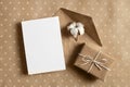 Greeting card mockup with gift box, envelope and cotton flower on craft paper background Royalty Free Stock Photo