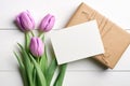 Greeting card mockup with gift box and tulip flowers on white wooden background