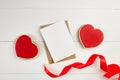 Greeting card mockup with paper envelope and red ribbon and heart shaped ginger snap cookie on white table Royalty Free Stock Photo
