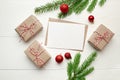 Greeting card mockup with red christmas decorations, gift boxes and fir tree branches on white Royalty Free Stock Photo