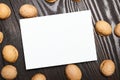 Greeting card mockup with walnut shells on wooden background, top view, flat lay. White blank holiday card on brown table Royalty Free Stock Photo