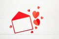 Greeting card mockup, white blank card with paper envelope and red parer hearts on wooden table background