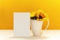 Greeting card mockup with white cup and sunflowers. Empty postcard with space for text. Template with porcelain cup and yellow
