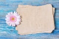 Greeting card with old blank paper and pink Gerbera daisy flower on blue wooden background Royalty Free Stock Photo