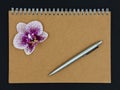 Notebook with pen and orchid flower. Copy space. Royalty Free Stock Photo