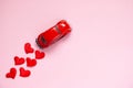 Greeting card with red hearts and a toy car on a pink background. Valentine`s day holiday concept. Flat lay, copy space Royalty Free Stock Photo