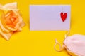 Greeting card template. Close-up of a beautiful yellow blossom of flower and a empty tag with a red heart on it and a pink fabric Royalty Free Stock Photo