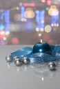 Greeting card template made of blue candle with blue ribbon, silver christmas balls, silver string of beads and colorful bokeh lig Royalty Free Stock Photo