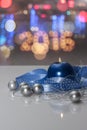 Greeting card template made of blue candle with blue ribbon, silver christmas balls, silver string of beads and colorful bokeh lig Royalty Free Stock Photo