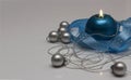 Greeting card template made of blue candle with blue ribbon, silver christmas balls and silver string of beads