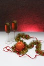 Greeting card template made of golden and green tinsel with red christmas balls, red ribbon, orange candle and two glasses of cham Royalty Free Stock Photo