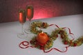 Greeting card template made of golden and green tinsel with red christmas balls, red ribbon, orange candle and two glasses of cham Royalty Free Stock Photo