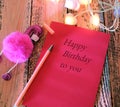 Greeting card with text Happy Birthday to you and Pen with toy pink flamingo . In dark settings. Concept of love and romance