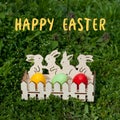 Greeting card with text Happy Easter in English. wooden egg cup with painted Easter eggs standing on green grass Royalty Free Stock Photo