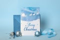 Greeting card with text Merry Christmas, envelope and balls on light blue background Royalty Free Stock Photo