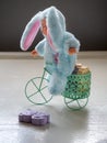 Greeting card on the topic of hygiene. A toy in a suit of a hare on a bicycle delivers soap to children