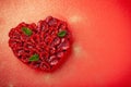 Greeting card with Valentine`s Day. confectionery Raspberry tart with mint in the form of a heart, lies on a red background