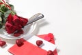 Greeting card for Valentine`s Day or Women`s Day. Red roses with ribbon on a white plate of the gala table and a love letter wit Royalty Free Stock Photo