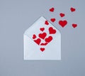 Greeting holiday card with red hearts flying from envelope over grey background.