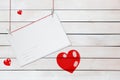 Greeting paper card and three red hearts on wooden white background with copy space