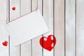 Greeting paper card and three red hearts on wooden white background with copy space