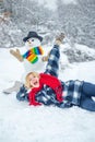 Greeting snowman. Snowman and funny female model standing in winter hat and scarf with red nose. Cute snowman at a snowy Royalty Free Stock Photo