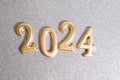 Greetings background with empty space. Happy new year card. Golden figures 2024 on a silver shining sparkling background