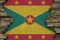 Grenada flag depicted in paint colors on old stone wall closeup. Textured banner on rock wall background