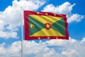 Grenada national flag waving in the wind on clouds sky. High quality fabric. International relations concept