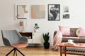 Grey armchair in living room interior with lamp and plant on cabinet next to beige sofa. Real photo Royalty Free Stock Photo