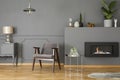 Grey armchair next to silver table in elegant living room interi