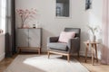 Grey armchair next to a wooden cupboard with dark vase in spacious, pink living room interior Royalty Free Stock Photo